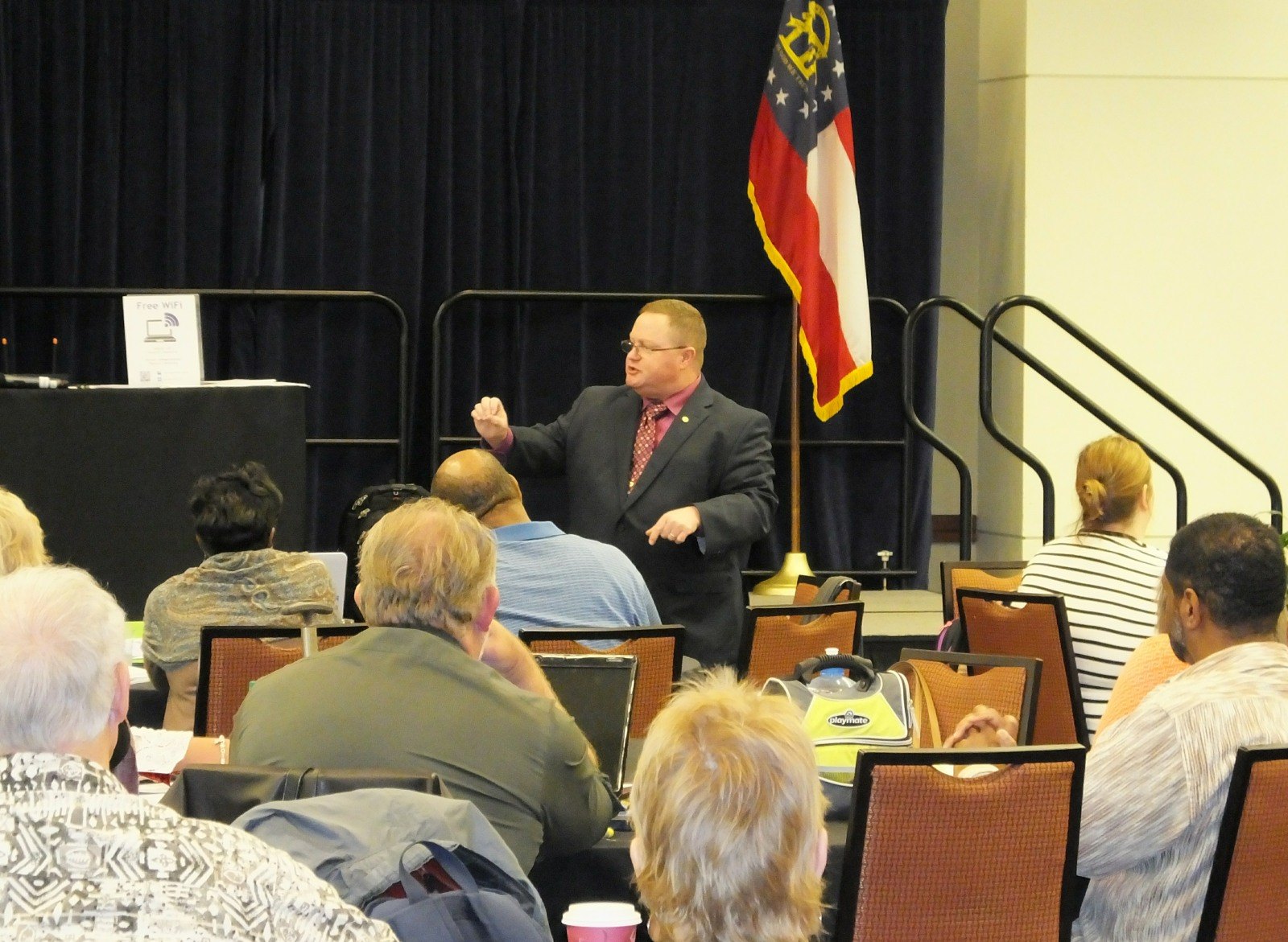 Eric Combs speaking on stage to a room of educators